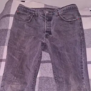 Säljer ett par klassiska grå/svart Levis 501 jeans i bra skick. De har en straight passform och är tillverkade i slitstarkt denim. W29 L32