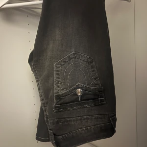 Svarta,gråa  jeans från True Religion - Säljer ett par snygga svarta jeans från True Religion i modellen Joey Low Rise Flare.Använt bara två gånger jätte bra skick skriv till mig innan ni köper🩷köpte för 1250