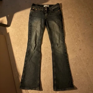 Lågmidjade jeans med bootcut - Säljer ett par snygga blå jeans med bootcut. De har en klassisk femficksdesign och är i bra skick. Perfekta för både vardag och fest! Passar till allt från sneakers till klackar.