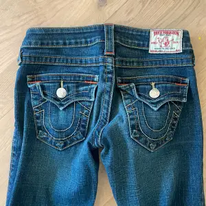 Säljer ett par snygga blå jeans från True Religion. De har coola broderade fickor med knappar och en bootcut-stil. Perfekta för en avslappnad look! 🕶️ OBS! Dragkedjan är sönder 