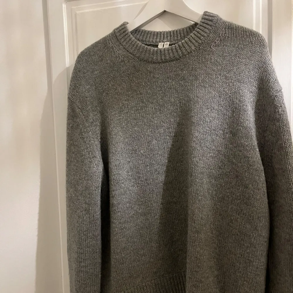 Säljer en stilren grå stickad tröja från arket i storlek S. Perfekt för kyliga dagar med sin mjuka och bekväma passform. Tröjan har långa ärmar och en klassisk rund halsringning. Tröjan är använd en gång och i nytt skick!. Neuletakit & Villapaidat.