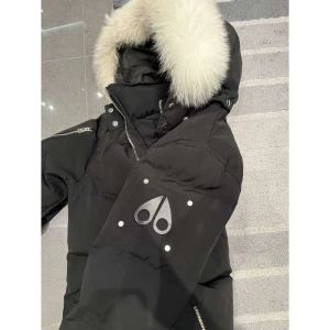 Svart dunjacka från Moose Knuckles - Säljer en svart dunjacka från Moose Knuckles med en lyxig pälsfodrad huva. Jackan har en snygg broderad logga på insidan och dragkedjor på ärmarna.