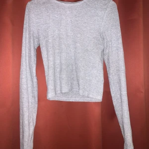 Grå långärmad crop tröja från H&M - Jättefin långärmad tröja från H&M, sparsamt använd - inga defekter, märken, slit mm.