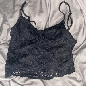 Svart spetslinne från FB Sister - Snyggt svart spetslinne från FB Sister i storlek S. Perfekt för en utekväll eller fest! Linnet har justerbara axelband och en vacker spetsdesign som ger en elegant touch. Passar bra till både jeans och kjol.