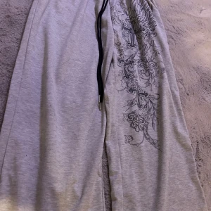 Grå mjukisbyxor med tryck - Säljer ett par grå mjukisbyxor med coolt tryck av kors och vingar på sidan. Helt nyskick och jätte mysiga