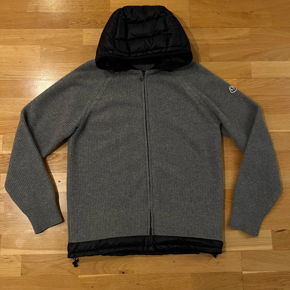 Säljer en snygg grå stickad jacka från Moncler med svart quiltad huva. Perfekt för höst, vår och svensk vinter! Den har en dragkedja framtill och är i mycket bra skick 10/10. Jackan är långärmad och har en normal passform M/L. Hör av er vid intresse eller frågor! . Takit.
