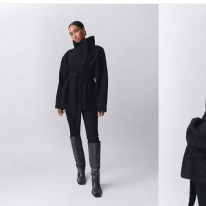 Svart kappa med knytband från Gina tricot  - Snygg svart kappa med knytband i midjan. Perfekt för höst och vinter. Den har en hög krage och långa ärmar. Den är ifrån Gina tricot och ät k storlek S vilket är slutsåld på hemsidan. Använd ett få tal gånger och har inga slitningar 