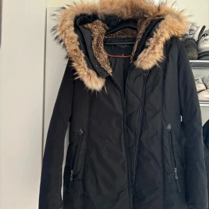Svart parkajacka från Hollies - Säljer en snygg svart parkajacka från Hollies i storlek 40. Jackan har en mysig pälskantad huva och dragkedja framtill. Perfekt för kalla vinterdagar! 🖤