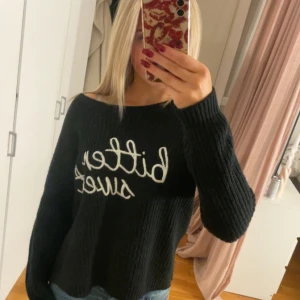 Svart stickad tröja med text - Säljer en svart stickad tröja med texten 'Bitter Sweet' i vitt på framsidan. Tröjan har en avslappnad passform och långa ärmar, perfekt för kyliga dagar. Den är både stilren och bekväm, idealisk för vardagsbruk. Passar bra till jeans eller leggings för en casual look.