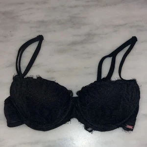 Svart  bh från PINK - Svart push up bh med rosa insida från Victorias Secret PINK. Storlek 32A (passar 70B). Den har spetsdetaljer och justerbara axelband för perfekt passform. Nypris ca 500kr.