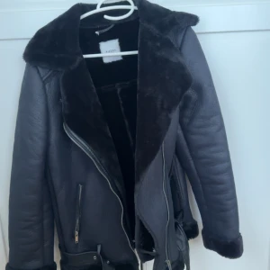 Svart skinnjacka med pälsdetaljer - Säljer en snygg svart skinnjacka från pisec med mjuka pälsdetaljer på kragen och insidan. 