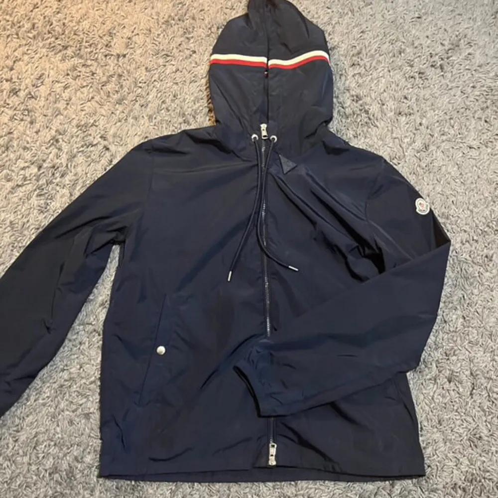 Helt ny marinblå Moncler Windbreaker, den är använd 2 gånger. Men den har inga skador eller liknande, den är fortfarande i 10/10 skick. Jackan har en fungerande Nfc Scan. Det är storlek 3 vilket motsvarar L, men passar även M. Rekommenderar starkt!. Jackor.