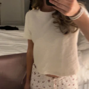 Vit kortärmad topp med knappar - Säljer en söt vit topp med korta ärmar och guldiga knappar på axeln. Aldrig använd. Säljer då den inte kommer till användning❤️❤️