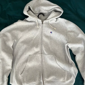 Grå hoodie från Champion - Säljer en grå hoodie från Champion i storlek XL men sitter som en Large. Har använts varsamt och är i väldigt bra skick