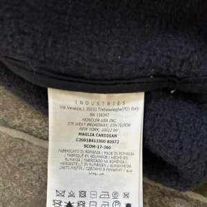 Mörkblå cardigan från Moncler - Säljer en snygg mörkblå cardigan från Moncler i storlek M. Den har en dragkedja framtill och en praktisk huva. Perfekt för höst och vår, med Monclers ikoniska logga på ärmen. Passar både till vardags och lite finare tillfällen. 🧥✨