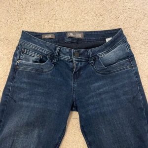 Blå jeans från LTB - Säljer ett par snygga blå jeans från LTB i modellen Valerie. De är lågmidjade och har en bootcut-stil som ger en skön retrovibe. Perfekta för både vardag och fest! Jeansen är i bra skick skit. Storleken motsvarar S. Kolla bilder för mått!