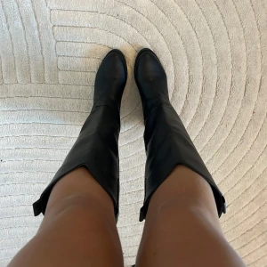 Svarta stövlar i skinn - Snygga svarta stövlar i skinnimitation med en klassisk design. De har en låg klack på 5cm och spetsig tå. Perfekta för höst och vinter, och funkar lika bra till vardags som till fest. Skorna är helt nya och oanvänd, då jag har ett till par liknande.