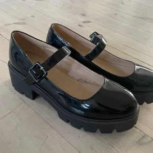 Svarta lackade Mary Jane skor - Aldrig använda jätte söta svarta Mary Jane skor i lackat material med en rejäl klack och grov sula. Perfekta för både vardag och festliga tillfällen! Fin kvalitet, köpte för små!!