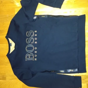 Hugo Boss tröja - Säljer en svart hugo boss tröja med gula detaljer och text, den är i fint skick och passar mig som är ca 180 lång 😁