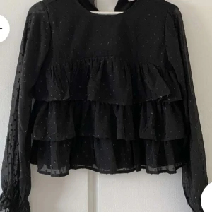Blus med volanger från Gina Young  - Säljer denna svarta blusen från Gina Young ❤️ Den är i superfint skick då den endast är använd ett fåtal gånger❤️(Bilden är lånad från Plick) skriv vid fler frågor eller bilder❤️