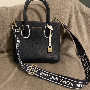 Navy handväska från Michael Kors - Snygg navy handväska från Michael Kors i skinn. Väskan har en justerbar axelrem med logotyp och guldfärgade detaljer. Perfekt för både vardag och fest! Pris kan diskutera.