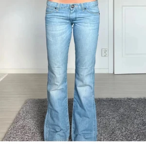 Ljusblå bootcut jeans - Säljer ett par ljusblå bootcut jeans i bra skick. De är lågmidjade och har en klassisk femficksdesign med knapp och dragkedja framtill. Perfekta för en avslappnad vardagslook eller att klä upp med klackar. Passar både vår och sommar och vinter om ni vill ha mer bilder skicka till mig så jag fixar