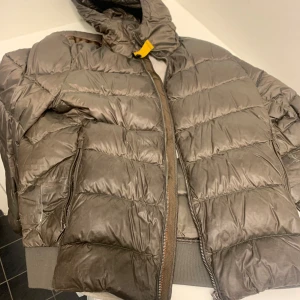 Parajumper vinterjacka - Säljer en brun pufferjacka med huva. Den har en dragkedja framtill och är quiltad för extra värme. Jackan är i acceptabelt skick med några skador(se bilderna). Perfekt för höst och vinter!