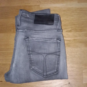 Grå jeansbyxor - Säljer ett par grå jeansbyxor i bra skick. De har en klassisk femficksdesign och är perfekta för vardagsbruk. Passformen är slim och de är tillverkade i ett bekvämt denimtyg. Perfekta för både höst och vår!