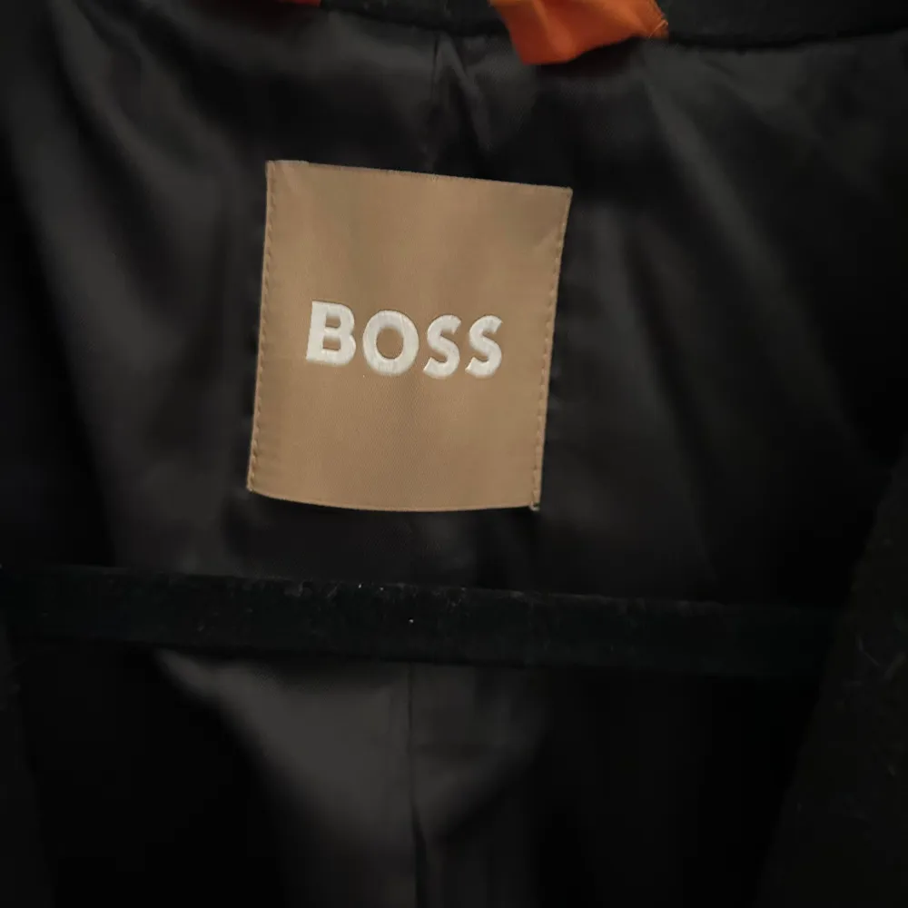 En äkta Hugo Boss kappa. Som är använd både hösten 2023 och våren 2024.Finns en knapp där framme och två fickor. Den är i ett använt skick men har inga synliga defekter. Den är i storlek M. . Jackor.