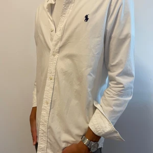 Polo Ralph Lauren Oxfordskjorta Vit - Utmärkt skick, inga alls defekter eller skavanker. Använd men varsamt skött. Riktigt snygg, funkar året runt. ORG. Pris 1595, mitt är endast 600.
