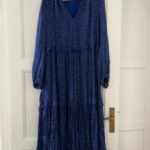 Mörkblå klänning Indiska stl L - Lite leomönster, v-ringad med volangdetalj på 2 ställen. Nyskick - endast använd vid 1 tilfälle.