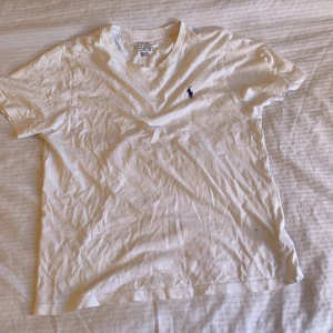 Ralph lauren t shirt - En vit Ralph lauren et shirt som har två hål på fram sidan av tröjan. Den är storlek xs men passar säkert S. 