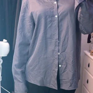 Grå skjorta från Shein - Säljer en stilren grå skjorta från Shein i storlek M. Skjortan har långa ärmar och knappar framtill. Perfekt för både vardag och fest!
