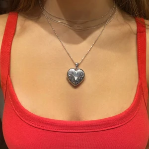 Heart Locket, Medaljong i Silver - En öppningsbar, hjärtformad medaljong och en kedja i äkta silver. 3 cm hög och 2,5 cm bred. Ett statement halsband som man kan ha två bilder i. Kedjan är ungefär 44 cm. Båda två har silver stämpeln. Priset kan diskuteras❤️
