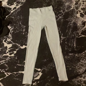 Randiga leggings - Säljer ett par snygga randiga leggings i en ljus färg. De är högmidjade och har en tight passform, perfekt för både vardag och träning. Materialet är mjukt och stretchigt, vilket gör dem superbekväma att ha på sig.