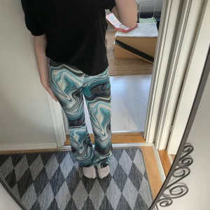 Färgglada mönstrade byxor från Bik Bok - Säljer ett par supercoola byxor från Bik Bok med ett unikt, färgglatt mönster i blått, svart och vitt. De är i en skön och stretchig material som sitter perfekt. Perfekta för att liva upp vilken outfit som helst! Aldrig använda, lappen sitter kvar!