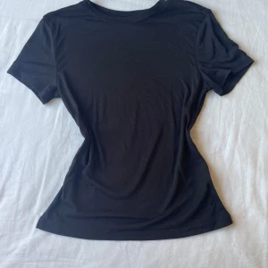 Figurnära T-shirt  - En svart figurnära T-shirt från H&M aldrig använd. Skriv för frågor, lite genomskinlig.