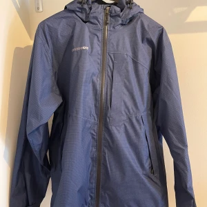 Blå regnjacka från Didriksons - Säljer en blå regnjacka från Didriksons i storlek Large. Perfekt för regniga dagar med sitt Storm System som håller dig torr. Den har en diskret rutig mönster och är långärmad. Passar bra för höst och vår.