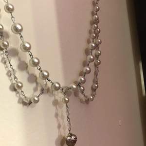 Ett kedjehalsband med vita vaxpärlor, med ett par matchande örhängen. Styckpris: halsband-70, örhängen-60 pris för båda-130 kr