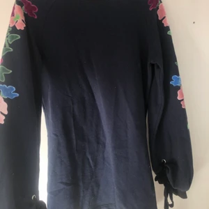 Klänninh från Juicy Couture - Supersöt klänning från Juicy Couture med blommor broderad på ärmarna. Köpt för några år sedan men bara använd 1 gång. Storlek S men passar Xs-M.