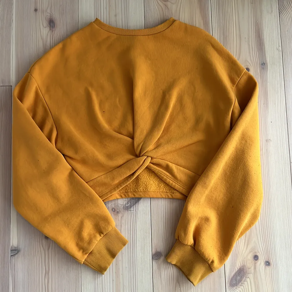 En gul/orange tröja med knut på framsidan. Är i bra skick. Tröjor & Koftor.