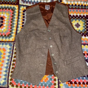 Mönstrad brun vest - Brun väst med subtilt mönster i storlek M! Baksidan är samma glansiga material som insidan:) märket är Sandwich. Kommer från rökfritt hem med katt!! Skriv om fler bilder önskas!