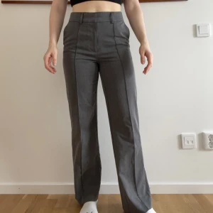 Gråa kostymbyxor - Ett par gråa kostymbyxor från NA-KD. Supersköna och satt som en smäck när mina lår var liiite mindre.  ”Sydda” pressveck och slits bak i hälen.    För referens är jag 168cm (med ganska korta ben). 