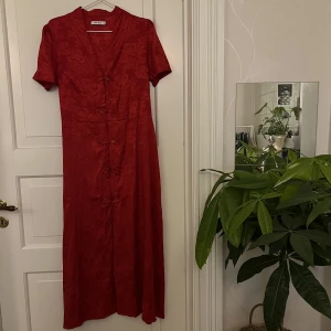 Röd långklänning🤍 - Röd långklänning med knytskärp i midjan. Diskret blommönster med fina detaljer. Från NAKD, storlek 38. Endast provad. Kan mötas i Göteborg eller skicka, köparen står för frakt. 