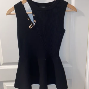 Cool topp från guess - Topp med fästnål som design, utsvängd nertill  Använd 1 gång och köpt i Spanien för ca 3 år sen, storlek xs men passar till S 