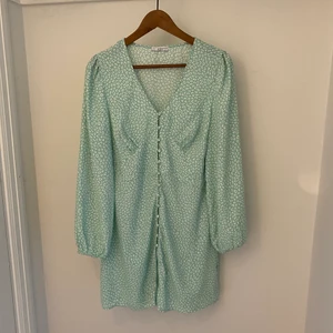 Sommarklänning från Nelly - Sommarklänning i grön färg med knappdetaljer på framsidan. Använd väldigt få gånger. I storlek L men är väldigt liten i storleken och därav  passar dig som är S/M. 