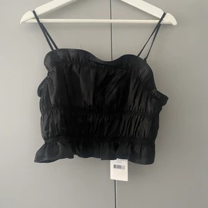 Svart satintopp från nakd  - Svart topp från nakd i storlek 38, oanvänd så prislappen är fortfarande kvar. Kan även skicka men då står köparen för frakten 