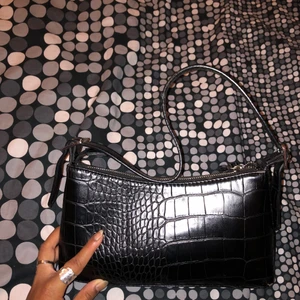 Axel väska - Axelremväska i svart ormskinn-material. Originellt från NAKD. 