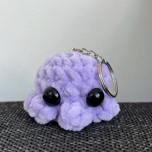 Virkad minibläckfisk-nyckelring - Egengjord, virkad minibläckfisk med nyckelring, i nyskick. Garnet är 100% polyester. Den är ca 6 cm lång och 5 cm hög. Den kostar 39kr totalt med frakt!