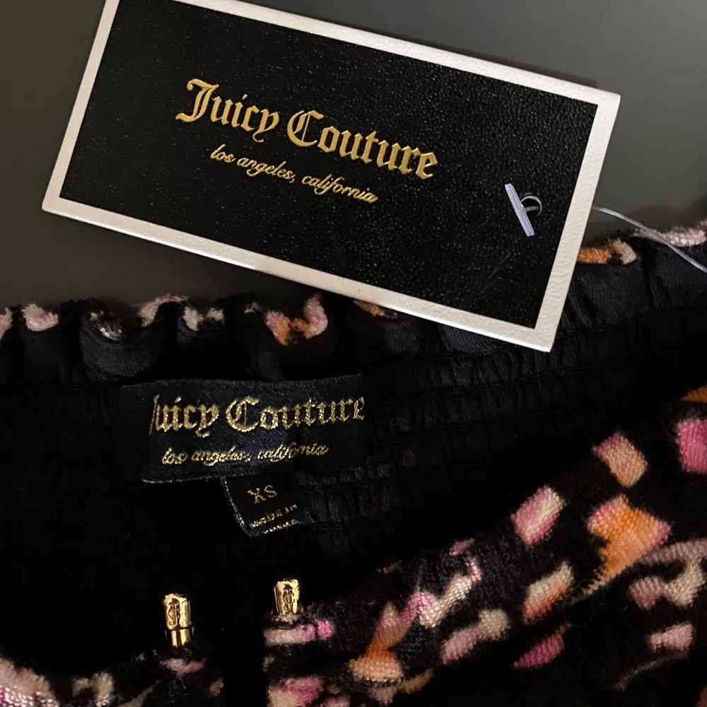 Svart Juicy Couture off-shoulder klänning med blommönster på. Klänningen är helt ny, aldrig använd, med lapp kvar. Nypris: 1995. Sitter fantastiskt fint på, i storlek XS. Säljs för 1750kr + frakt (57kr). . Klänningar.